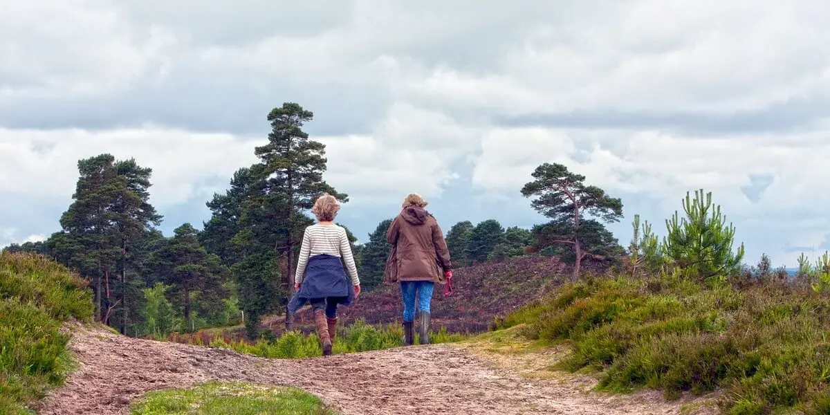 Twee vrouwen lopen over een heuvel.